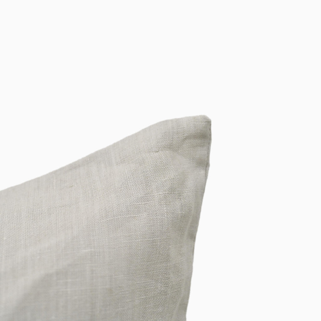 Light grey linen pillow cover shown at an angle highlighting fabric texture