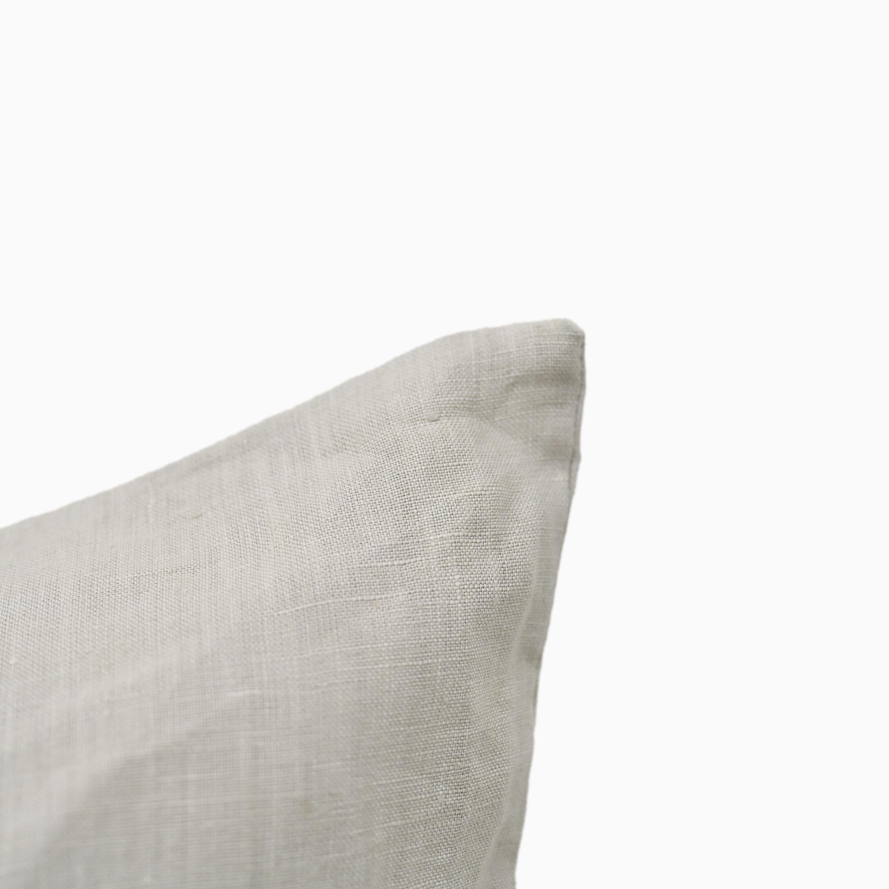 Light grey linen pillow cover shown at an angle highlighting fabric texture