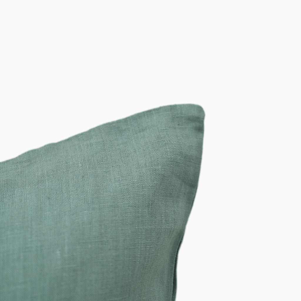 Close-up of teal linen pillow cover fabric texture and edge stitching