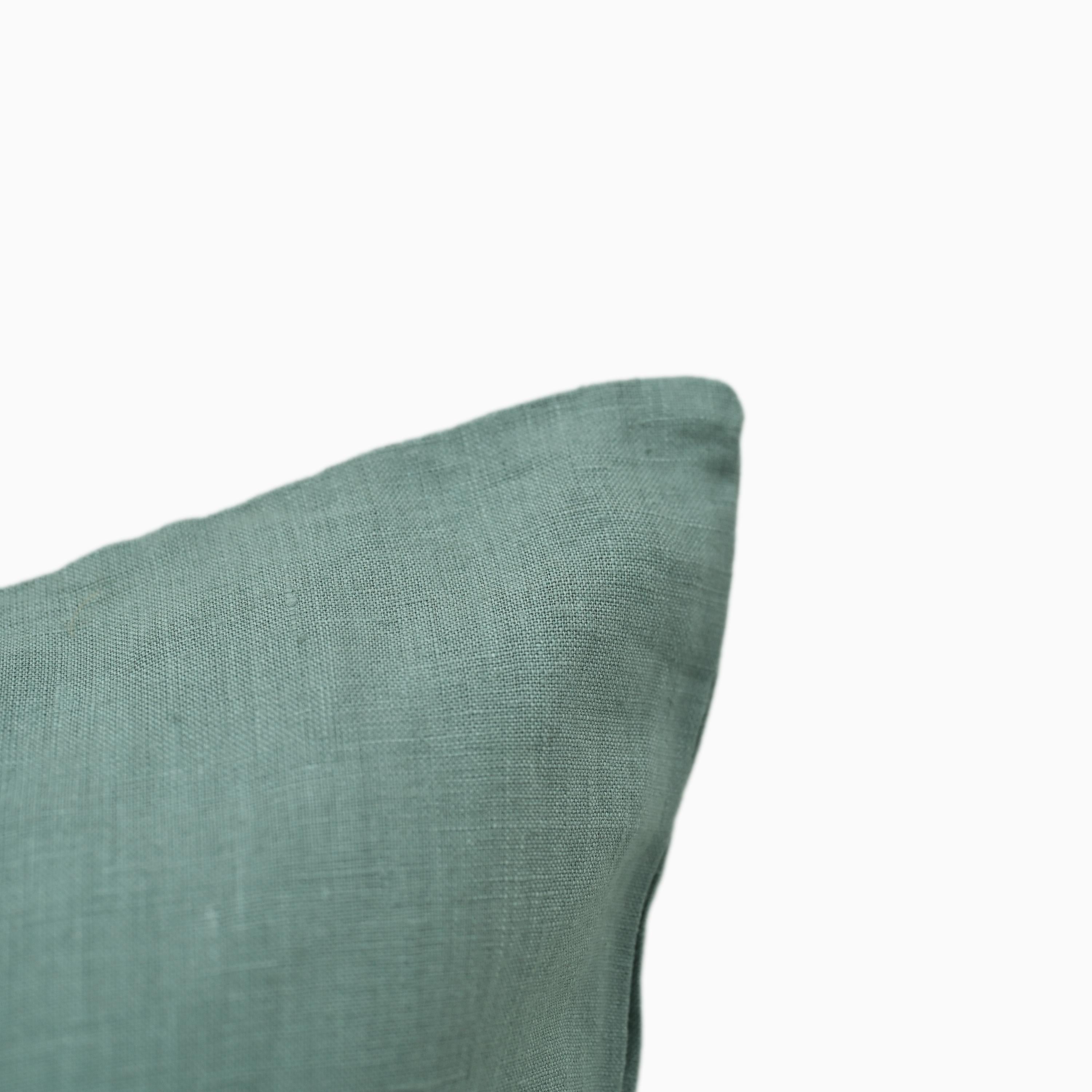 Close-up of teal linen pillow cover fabric texture and edge stitching