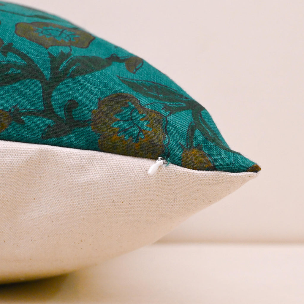 Teal wild rose block print linen cushion cover on a sofa