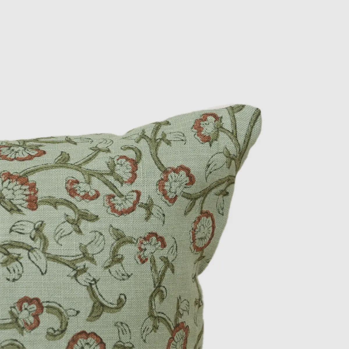 Close-up of rust terracotta jaal vine print on sage green linen