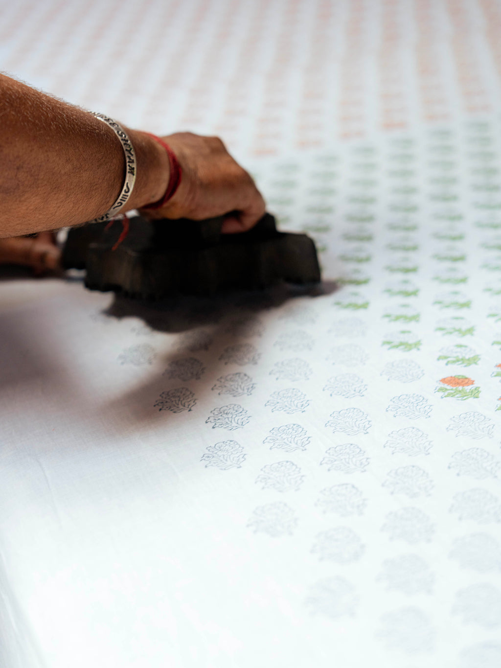 Artisan hand block printing the floral pattern onto linen fabric